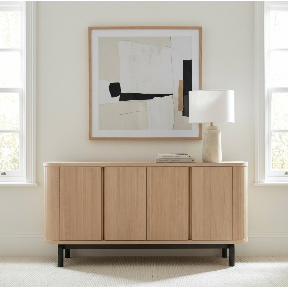 Wooden sideboard in a room with abstract art and a lamp.